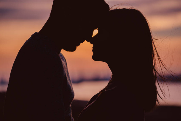 若いですカップルのシルエット持っていますロマンチックな瞬間に対して夕日の背景 - 写真・画像