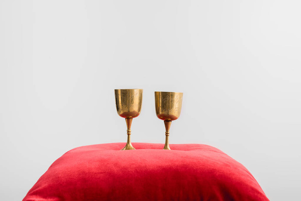 xícaras de ouro no travesseiro vermelho isolado no branco
 - Foto, Imagem