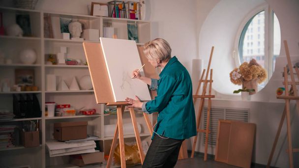 A young woman sketching an abstract tree on the white canvas - 写真・画像