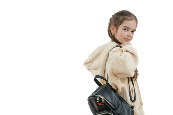 Приваблива маленька студентка брюнетки в бежевому светрі з чорним рюкзаком дивиться на камеру над її плечем, ізольована на білому тлі, копія
 - Фото, зображення