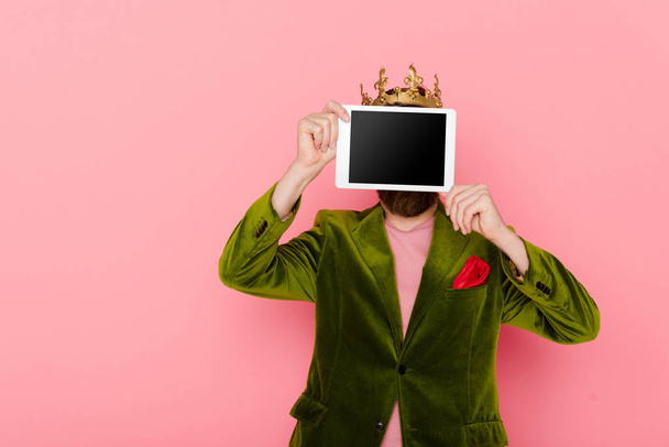 man with crown holding digital tablet with copy space isolated on pink  - Фото, зображення