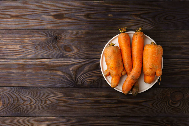 Άσχημα καρότα σε λευκό επίπεδο πιάτο. - Φωτογραφία, εικόνα