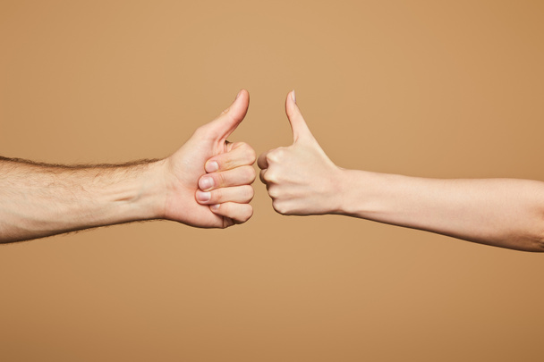 oříznutý pohled na muže a ženu ukazující palce izolované na béžové - Fotografie, Obrázek