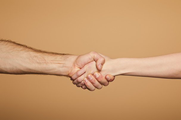 cropped view of man and woman holding hands isolated on beige - Foto, Imagen