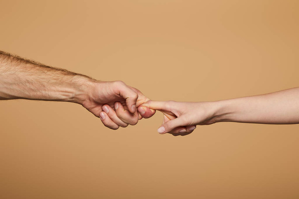 ostříhaný pohled na muže a ženu držící prsty izolované na béžové - Fotografie, Obrázek