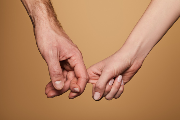vue recadrée de l'homme et de la femme tenant les doigts isolés sur beige
 - Photo, image