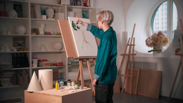 Genç bir kadın sanatçı, parlak renklerle onun resmini boyuyor. - Fotoğraf, Görsel