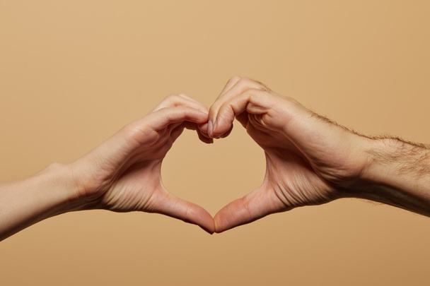 vista cortada de homem e mulher mostrando gesto do coração isolado no bege
 - Foto, Imagem