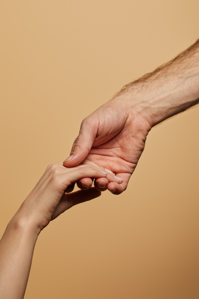 cropped view of man holding woman hand isolated on beige - Foto, imagen