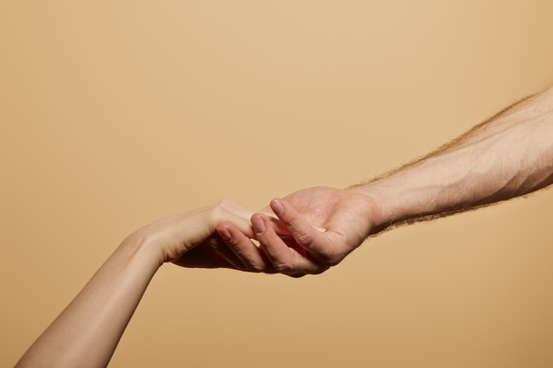 vista recortada del hombre sosteniendo la mano de la mujer aislada en beige
 - Foto, imagen