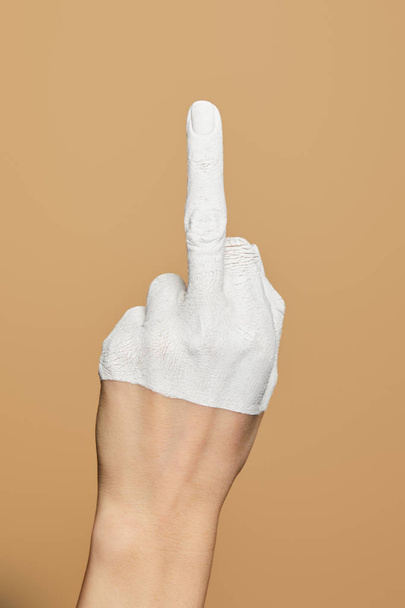 przycięty widok kobiety z białą, pomalowaną dłonią pokazującą środkowy palec odizolowany na beżu - Zdjęcie, obraz