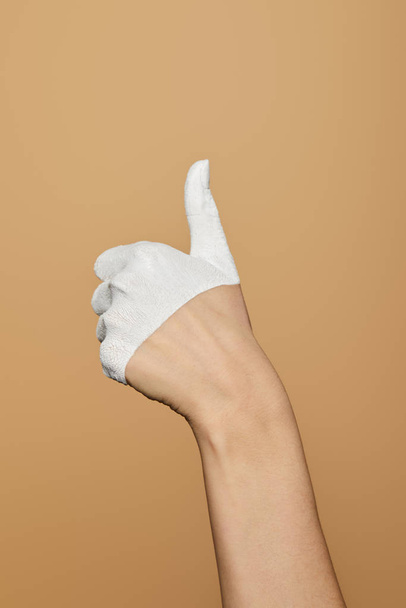 cropped view of woman with white painted hand showing thumb up isolated on beige - Fotoğraf, Görsel