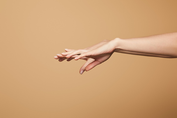 abgeschnittene Ansicht weiblicher zarter Hände isoliert auf beige - Foto, Bild
