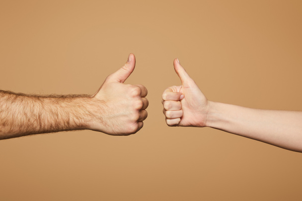 cropped view of man and woman showing thumbs up isolated on beige - Fotó, kép