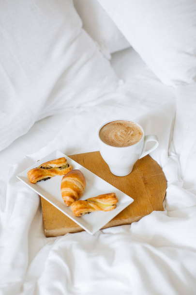 cup of morning coffee with fresh baked croissants on wooden pate on white bed background - Valokuva, kuva