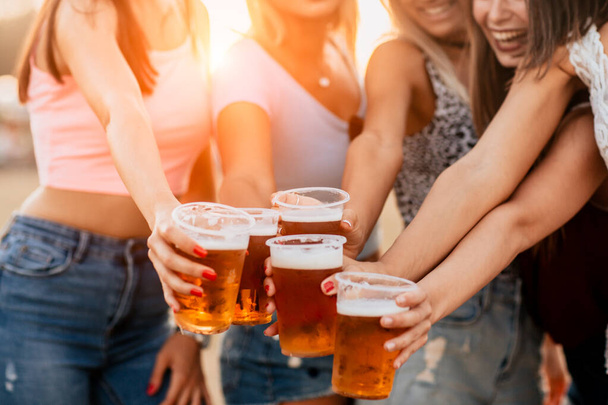 divertenti giovani donne ridendo e bevendo birra nei fine settimana del festival musicale
 - Foto, immagini