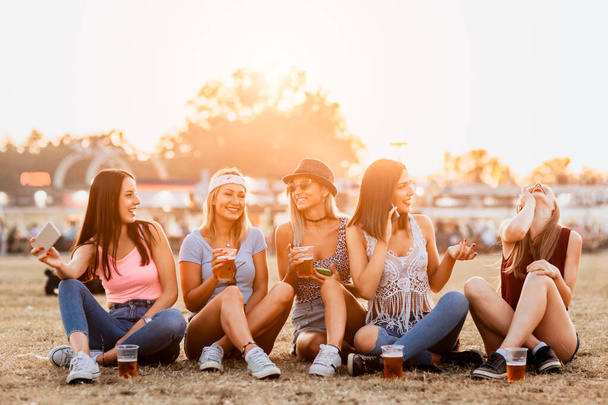 good-looking young women drinking beer and enjoying start of music weekends on festival  - Фото, изображение