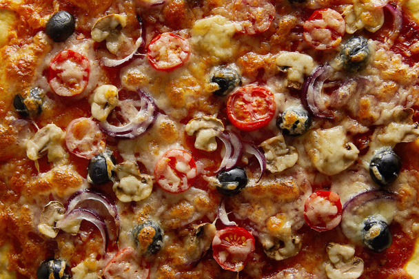 Bovenaanzicht van heerlijke pizza met kerstomaten, olijven en Parmezaanse kaas - Foto, afbeelding