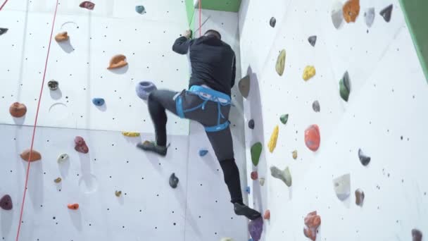 Man climbing indoor boulder wall. Practicing climbing with ropes - Footage, Video