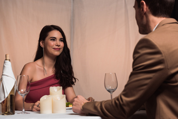 happy, elegant woman smiling at boyfriend while sitting in restaurant together - Photo, Image