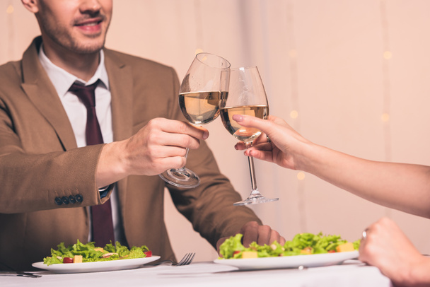 levágott kilátás férfi csörömpölés pohár fehér bor barátnő, miközben ül az étteremben - Fotó, kép