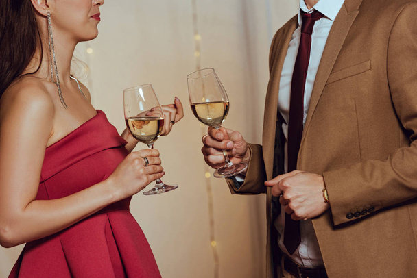 cropped view of elegant man and woman holding glasses of white wine in restaurant - Foto, immagini