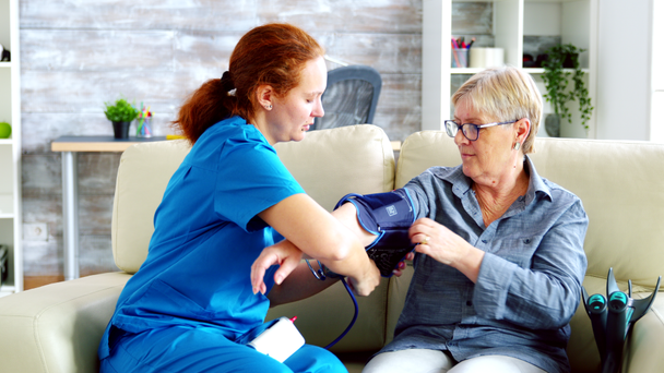 Žena lékař měření krevního tlaku starší ženy - Záběry, video