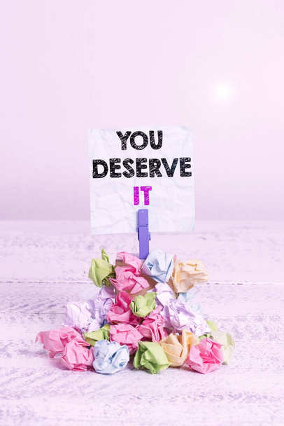 Handwriting text You Deserve It. Conceptual photo Reward for something well done Deserve Recognition award Reminder pile colored crumpled paper clothespin reminder white wooden space - Foto, imagen