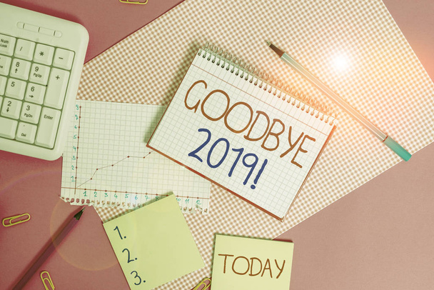 Handwriting text Good Bye 2019. Conceptual photo express good wishes when parting or at the end of last year Writing equipments and computer stuffs placed above colored plain table - Photo, Image