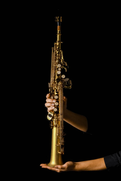 soprano saxophone in hands on a black background - Foto, afbeelding