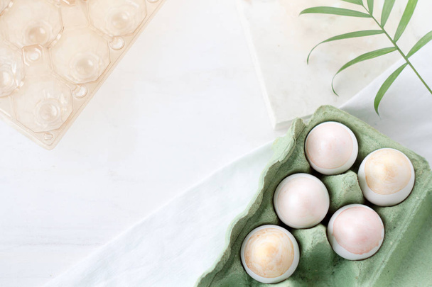 Natural Colored silver and gold  Eggs in craft egg box on a green background. Compositions in pastel colors. Easter concept. Flat lay, top view, selective focus - Foto, afbeelding