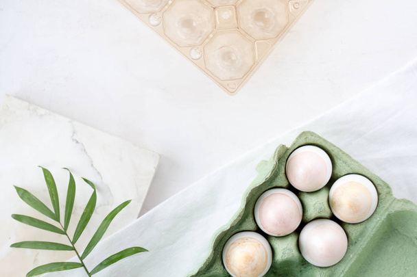 Natural Colored silver and gold  Eggs in craft egg box on a green background. Compositions in pastel colors. Easter concept. Flat lay, top view, selective focus - Foto, afbeelding
