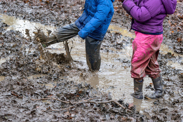 若い子供たちが泥の水たまりで遊んで - 写真・画像