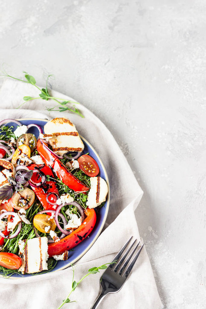 Grilled haloumi (halloumi) cheese salad witch tomato, baked pepper, micro green and onion on a blue plate. Keto diet, healthy food. - 写真・画像
