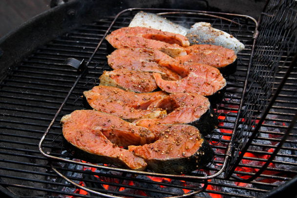 バーベキューグリッド上の照り焼きソースのサーモンフィレ。熱い石炭の上にマリネの赤魚ステーキ。バーベキューグリルでグリルしたサーモンステーキのクローズアップ. - 写真・画像