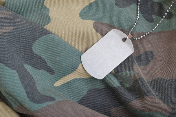 Grânulos militares prateados com etiqueta de cachorro no uniforme de fadiga de camuflagem
 - Foto, Imagem