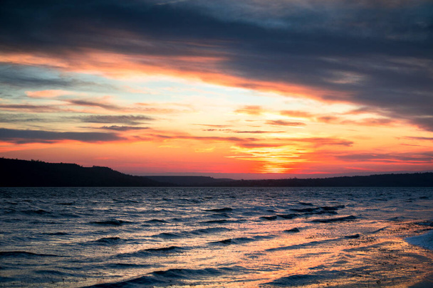 puesta de sol naranja y azul en el lago con pequeñas olas
 - Foto, Imagen