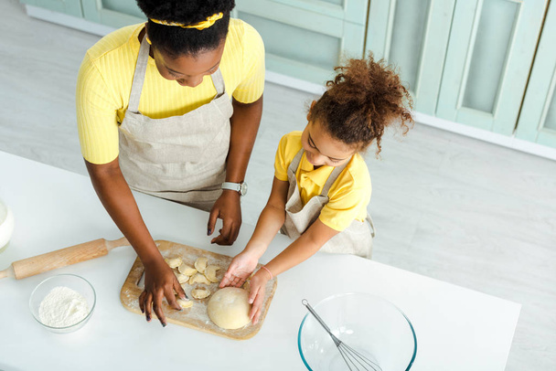 overhead view of african american mother and daughter sculpting dumplings  - Photo, Image