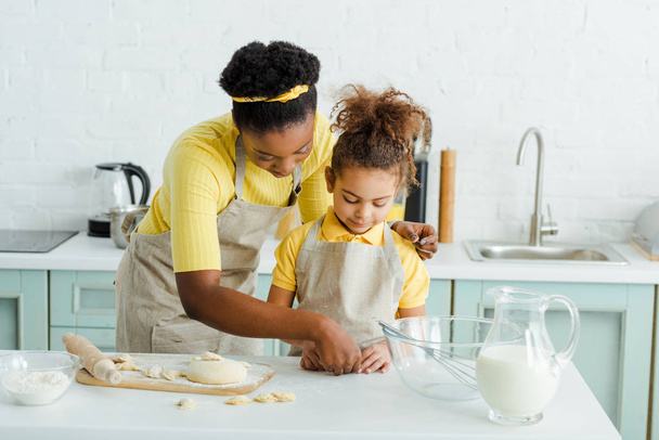african american mother near adorable daughter sculpting dumplings in kitchen  - Photo, Image