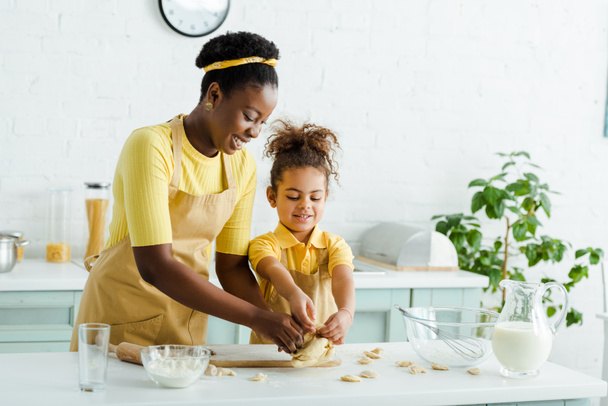 vidám afro-amerikai anya és boldog gyerek szobrászat gombóc a konyhában  - Fotó, kép