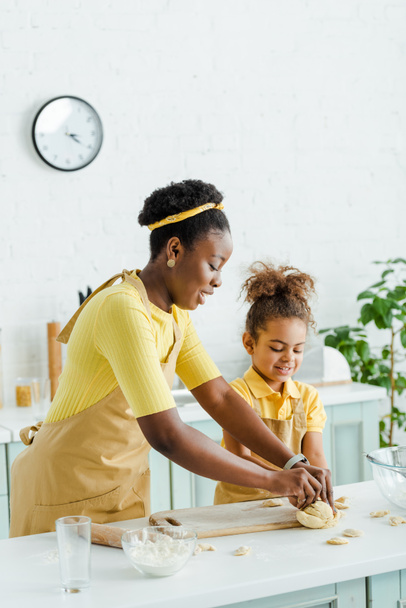 cheerful african american mother and happy kid sculpting raw dumplings in kitchen  - Photo, Image