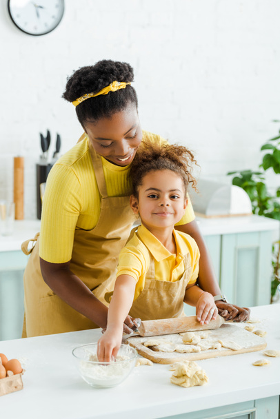 cute african american kid looking at camera near cheerful mother and dumplings on cutting board  - Photo, Image