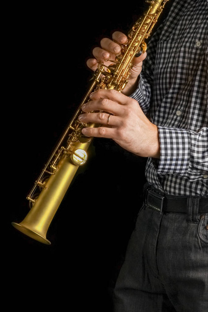 soprano saxophone in hands on a black background - Fotó, kép