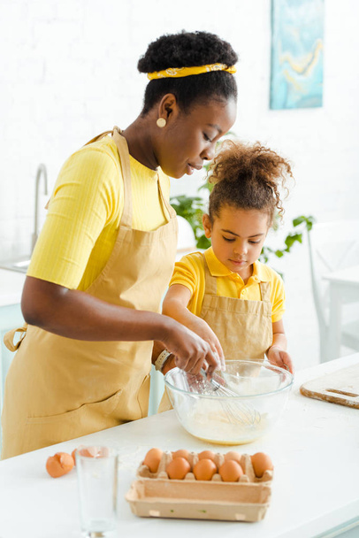 attractive african american mother holding whisk near bowl and daughter  - Photo, Image