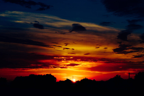 Hermosa puesta de sol naranja sobre las casas
 - Foto, imagen