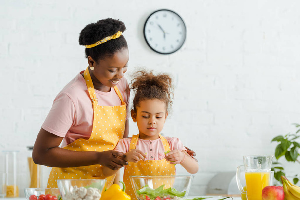madre afroamericana feliz y niño preparando ensalada
  - Foto, imagen