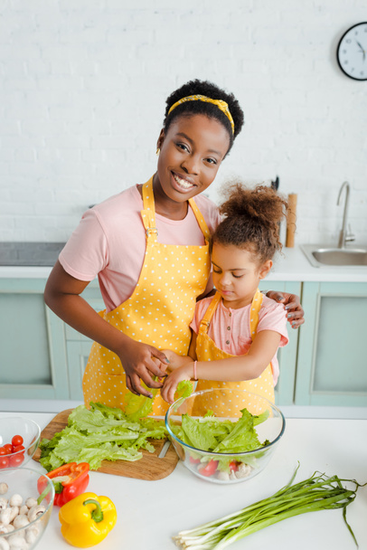 cheerful african american mother and cute child preparing salad  - Photo, Image
