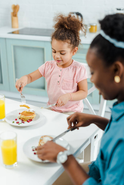 selective focus of happy african american kid and mother holding cutlery near pancakes  - Foto, immagini
