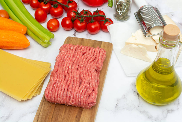 Minced meat with lasagna sheets, parmesan cheese, bottle of olive oil and vegetables for preparing Italian pasta - Photo, Image