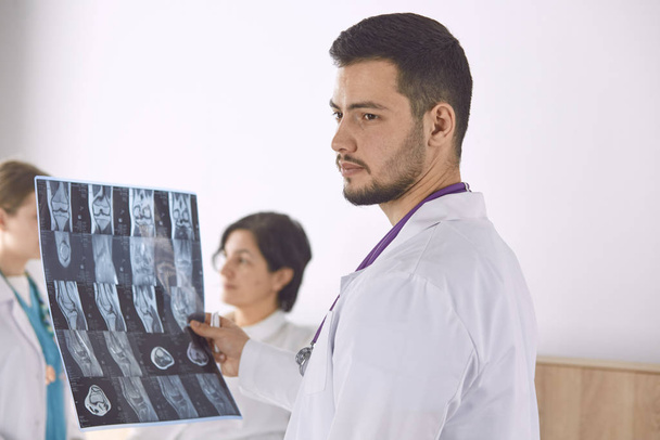 Доктор смотрит рентгеновские снимки пожилой женщины
 - Фото, изображение
